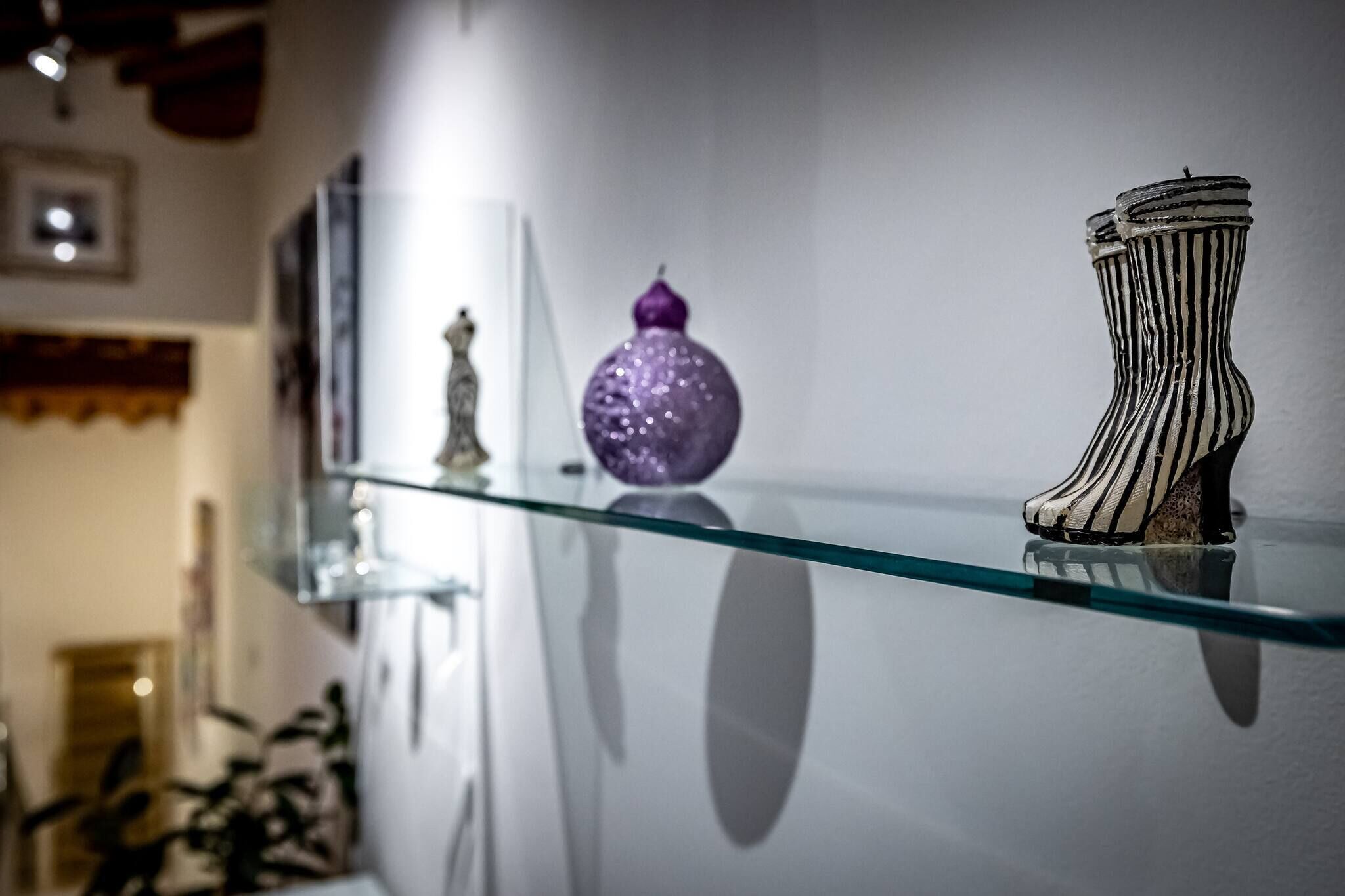 A glass shelf with decorative items, including a purple ornament and a striped vase.