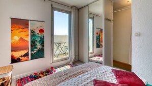 Ein Schlafzimmer mit einem Bett, einem Fenster, einem Balkon und zwei Bildern.
