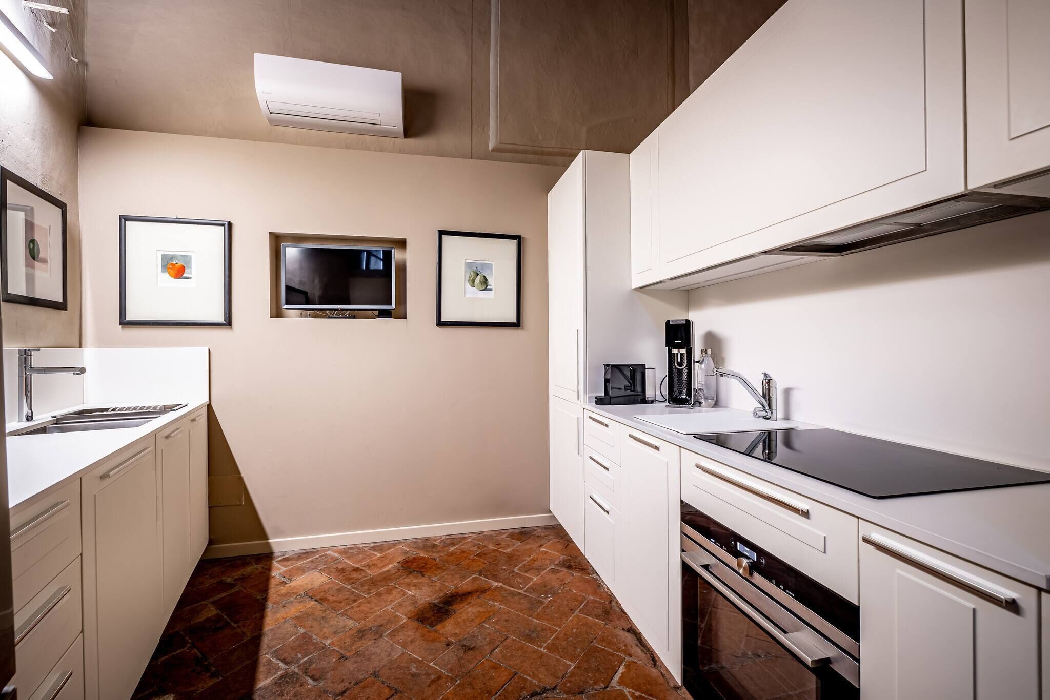 A modern kitchen with white cabinetry, a black countertop, and a tiled floor.