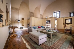 A spacious living room with high ceilings, a large sofa set, a coffee table, and a patterned rug. - Cantoria (Florence)