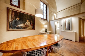 A dining area with a wooden table, chairs, a painting, and a lamp. - Cantoria (Florence)