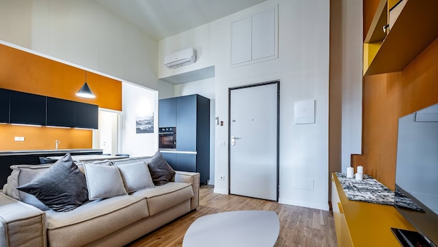 Una sala de estar moderna con sofá, mesa de centro y una cocina al fondo.