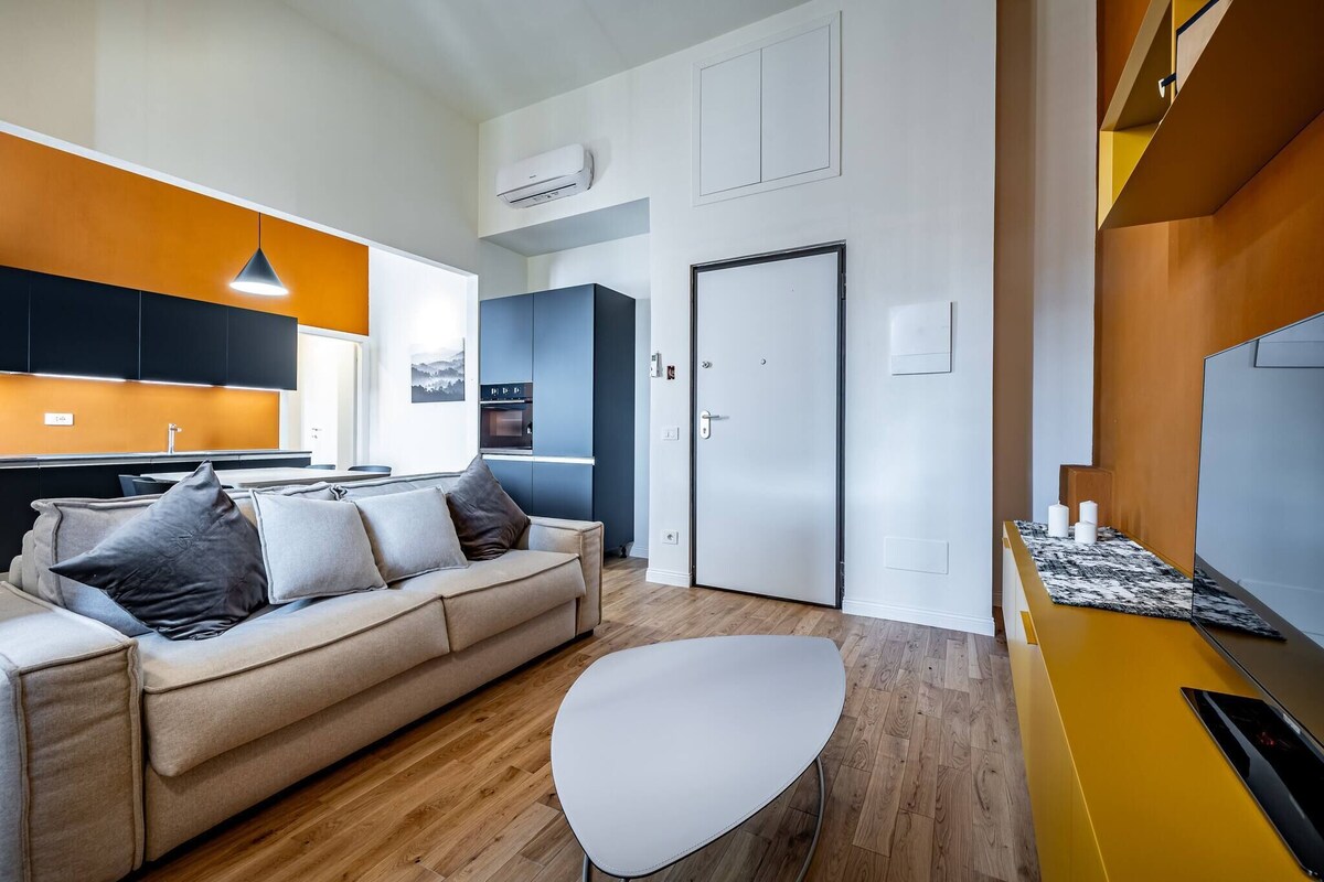 A modern living room with a sofa, a coffee table, and a kitchen area in the background.