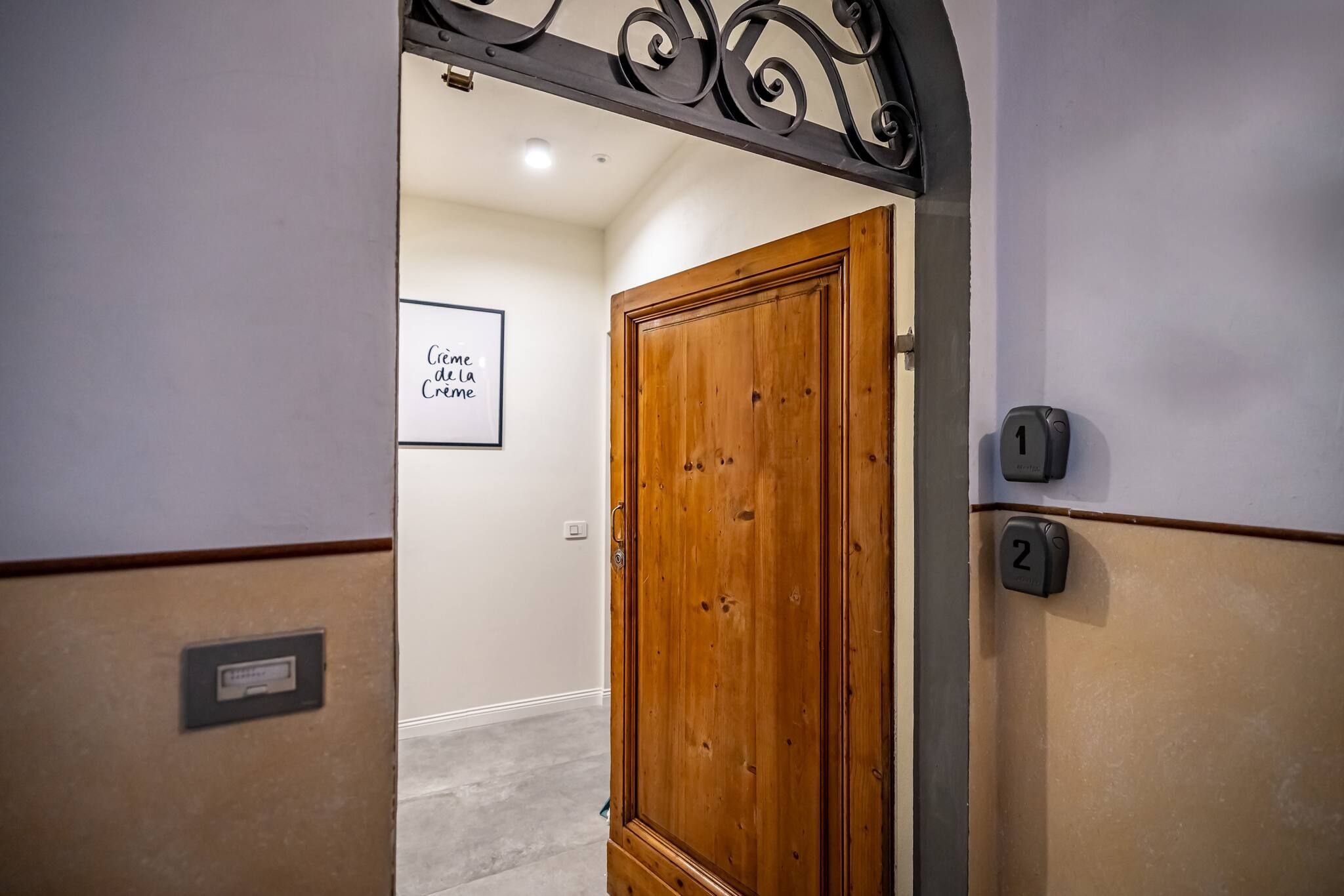 A hallway with a wooden door, numbered doors, and a sign on the wall.