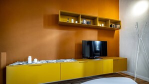 Una sala de estar moderna con un mueble amarillo para entretenimiento, un televisor de pantalla plana y una mesa blanca.