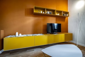 A modern living room with a yellow entertainment unit, a flat-screen TV, and a white table. - Romito Trilo (Florence)