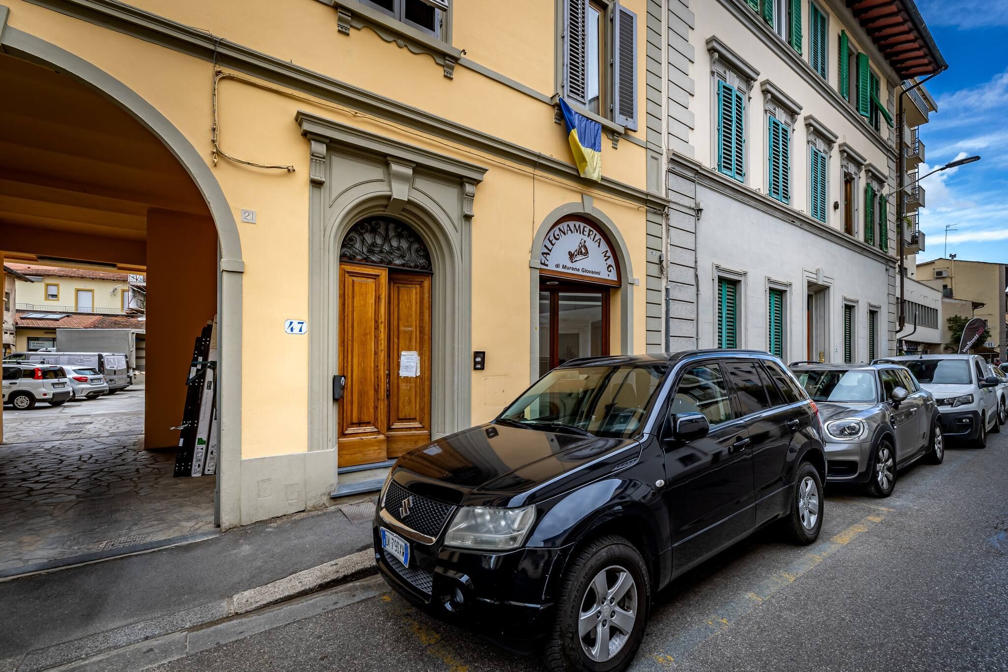 Un SUV negro estacionado frente a un edificio con un letrero que dice "Falegnameria di Mirena Gioia".