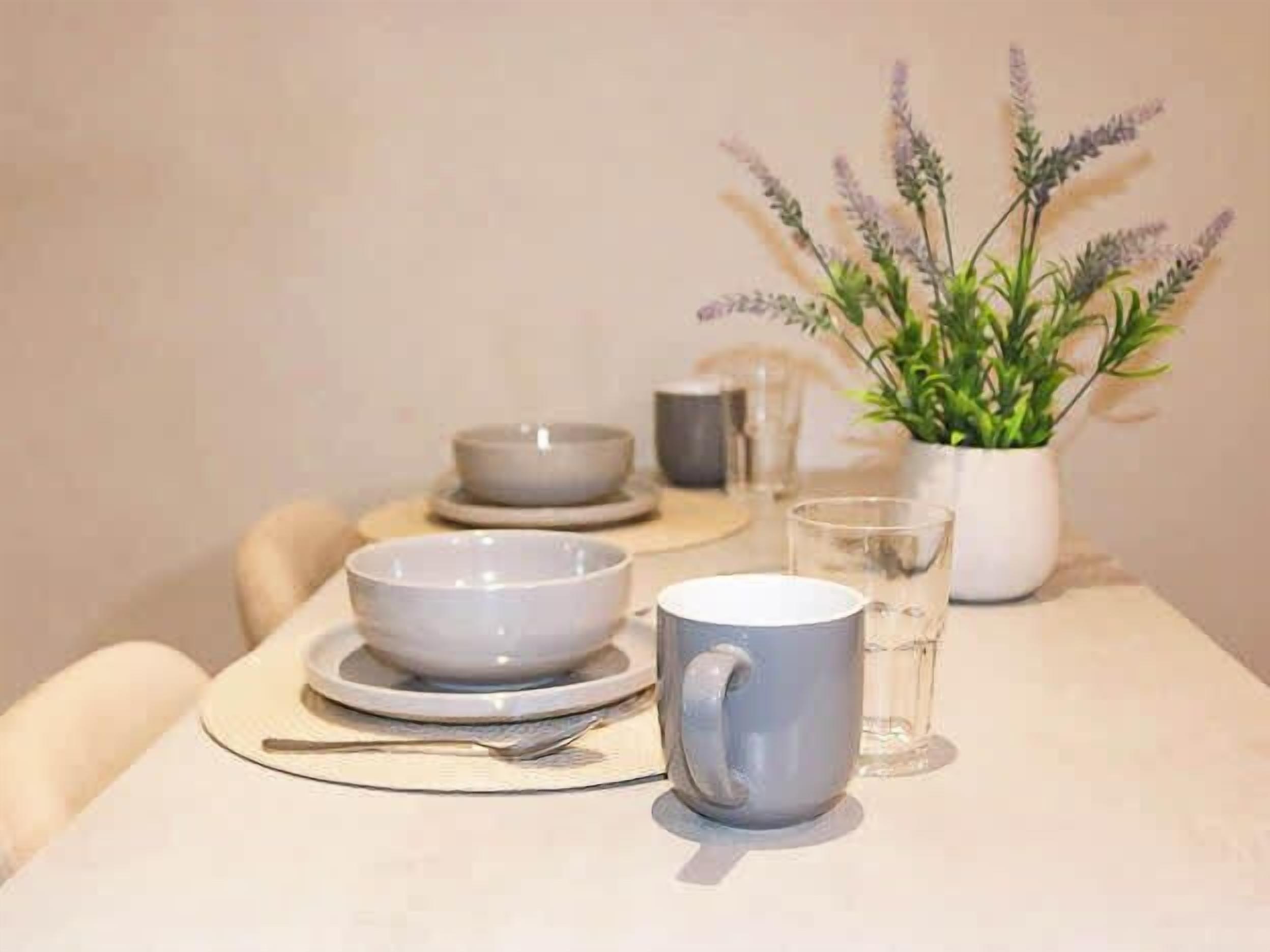 A dining table with a bowl, a mug, and a glass.
