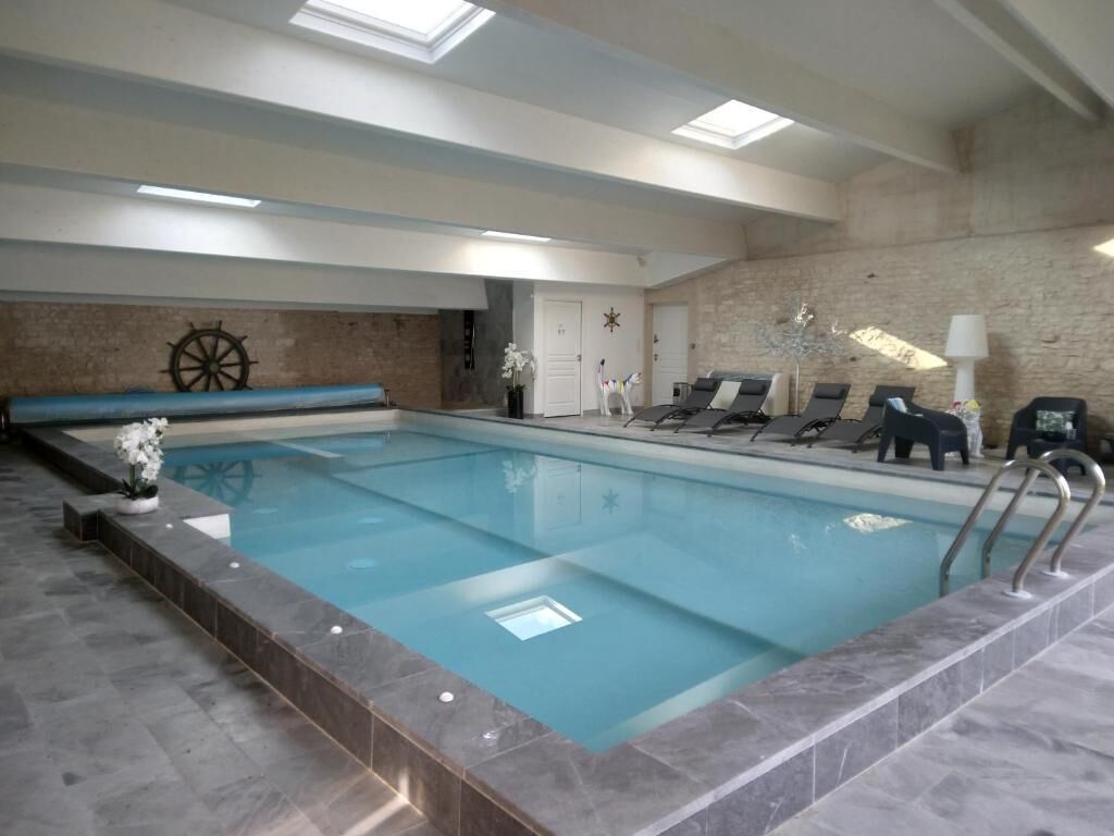 Ein Innenpool mit Steinwand, Schiffsrad-Dekoration und Liegestühlen.