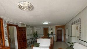Un grand espace de vie comprenant un canapé, des fauteuils, une table à manger et un coin cuisine.