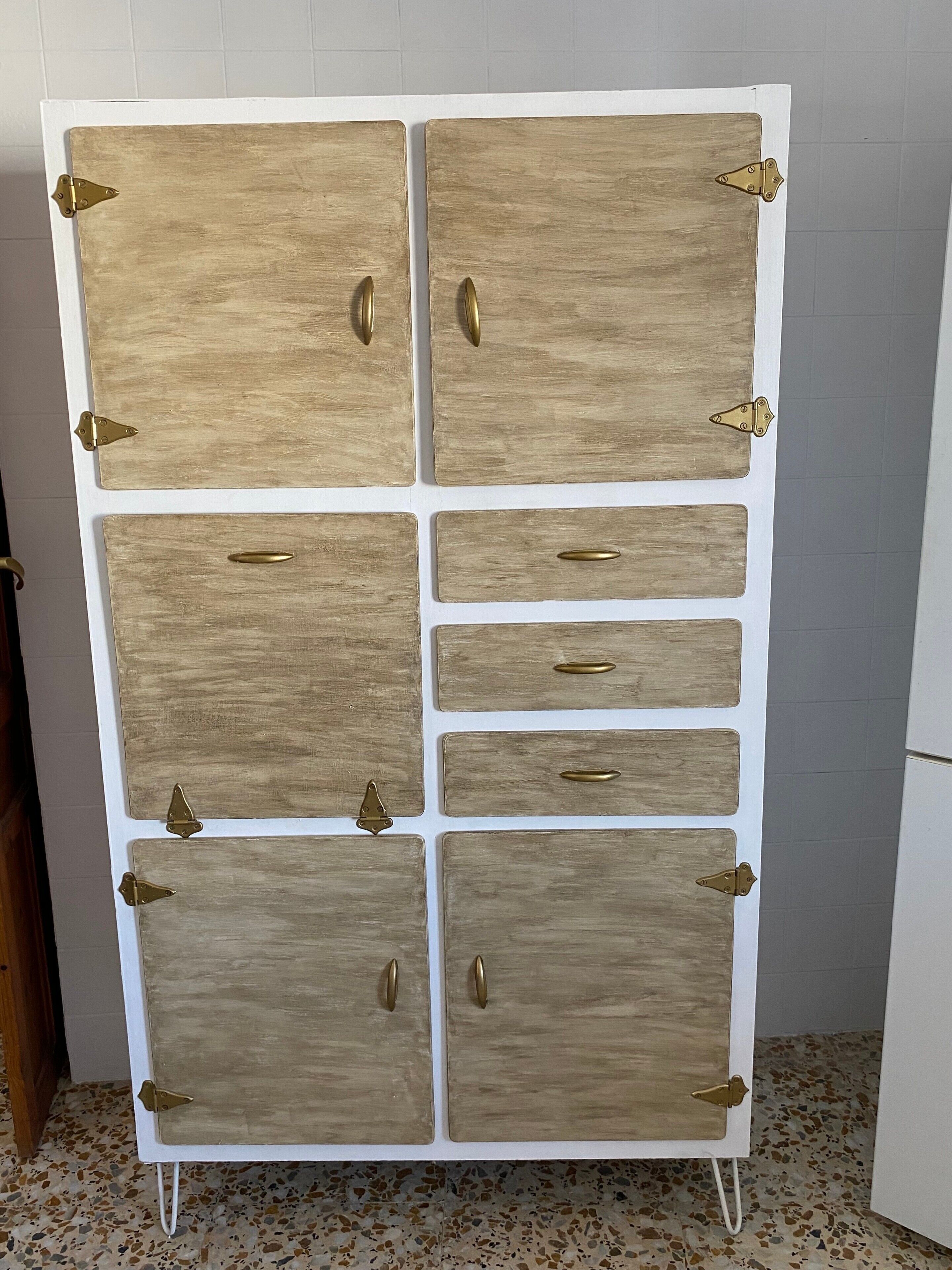 A tall, white storage unit with multiple compartments, each secured with brass hinges and handles.