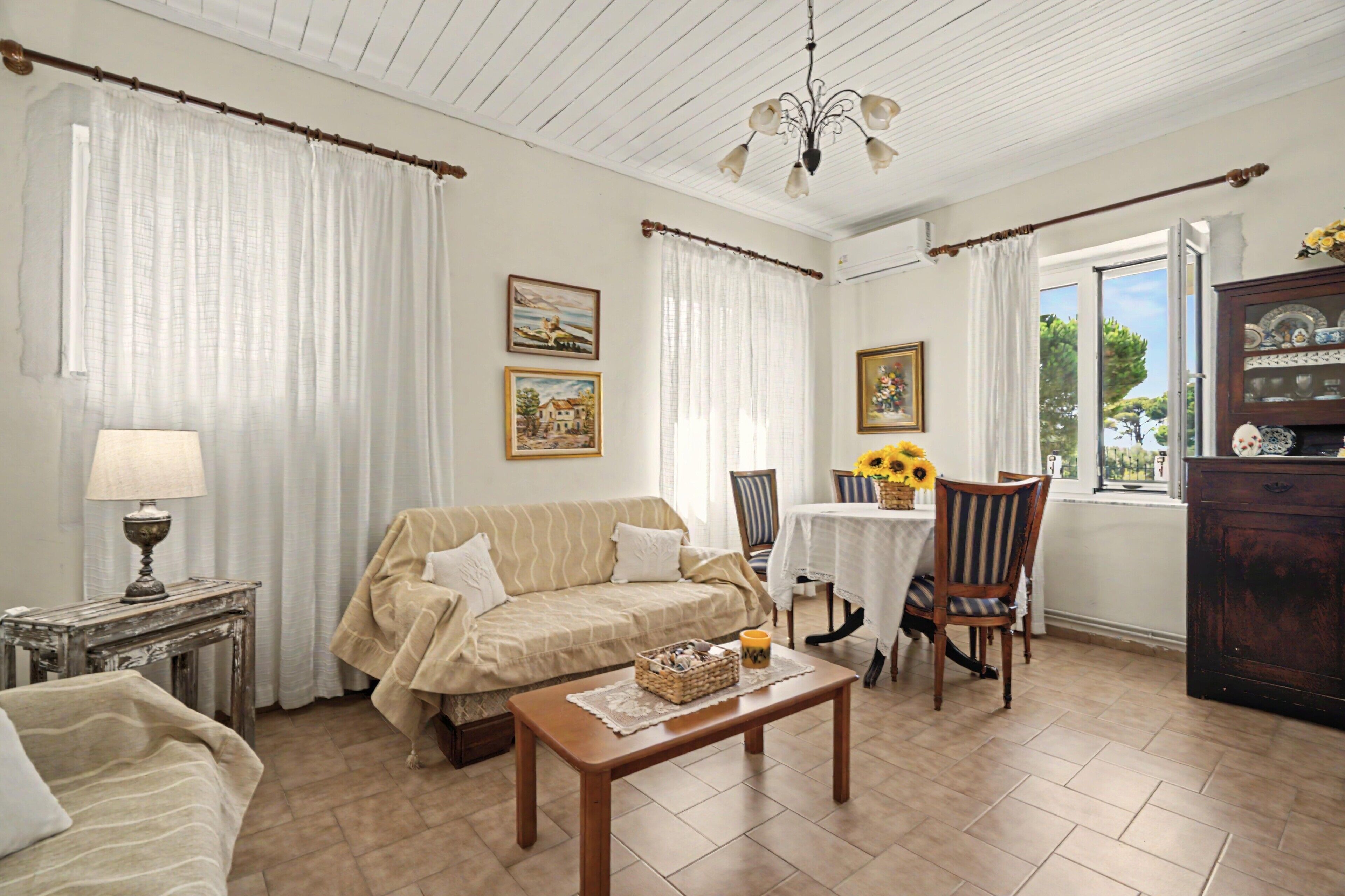 Una sala de estar acogedora con un sofá, una mesa con una cesta, una lámpara y vistas al exterior a través de una ventana.