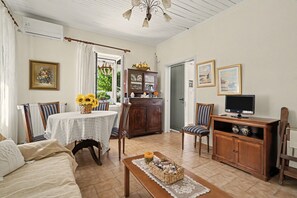Una sala de estar con una mesa de comedor, sillas, un sofá, un televisor y un aparador.