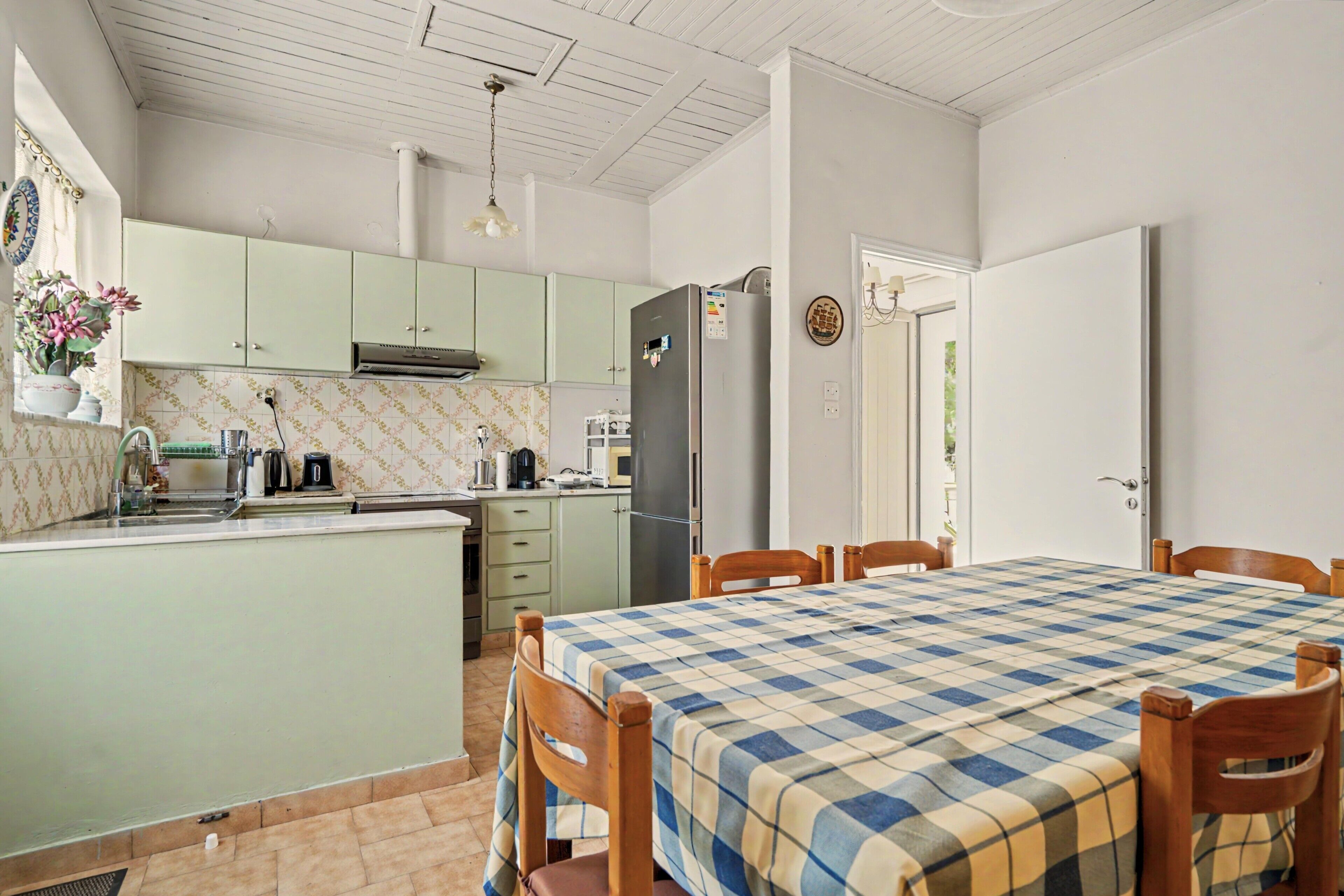 Cocina compacta con comedor, que incluye una isla central, refrigerador y microondas.