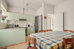 A compact kitchen with a dining area, featuring a central island, a refrigerator, and a microwave.