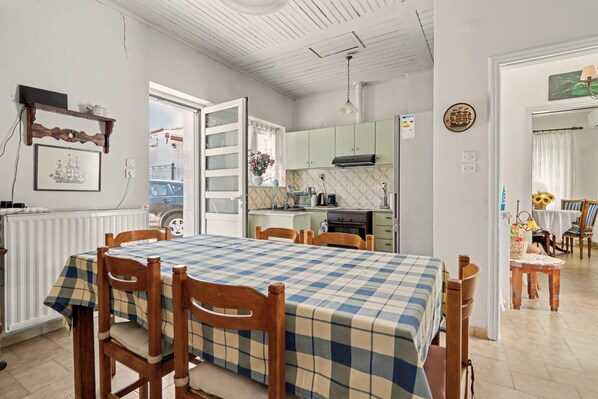 A dining area with a checkered tablecloth, wooden chairs, and a view into the kitchen.