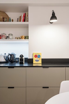 Eine Küche mit Wasserkocher, Kaffeemaschine und einer gelben Box auf der Arbeitsfläche.