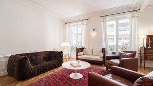 Un salon avec un canapé marron, une table basse blanche et un tapis à motifs.