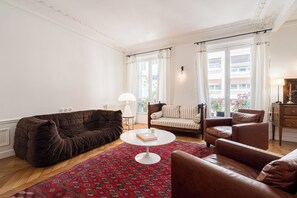 Ein Wohnzimmer mit einem braunen Sofa, einem weißen Couchtisch und einem Teppich mit Muster.