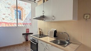 A kitchen with a window, a stove, a sink, and cabinets.