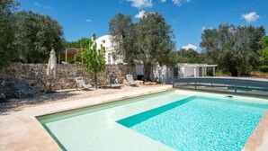 Ein Pool mit einer Steinmauer, Liegestühlen und einer Pergola.