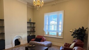 Ein großzügiger Wohnraum mit Kamin, einem großen Fenster und einer Kristallleuchtre.'