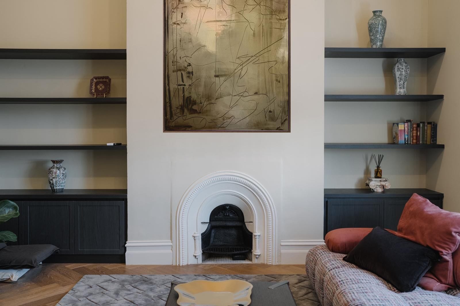 Una sala de estar con chimenea, estanterías y objetos decorativos.