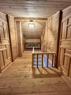 A wooden hallway with a bench, wooden walls, and a stone pillar.