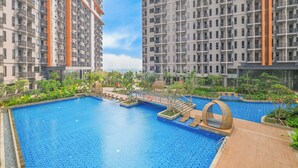 Edificio residencial con piscina, rodeado de vegetación y cielo despejado.