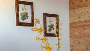 Een kamer met een ruitjesbank, een houten dressoir en twee ingelijste botanische prints aan de muur.
