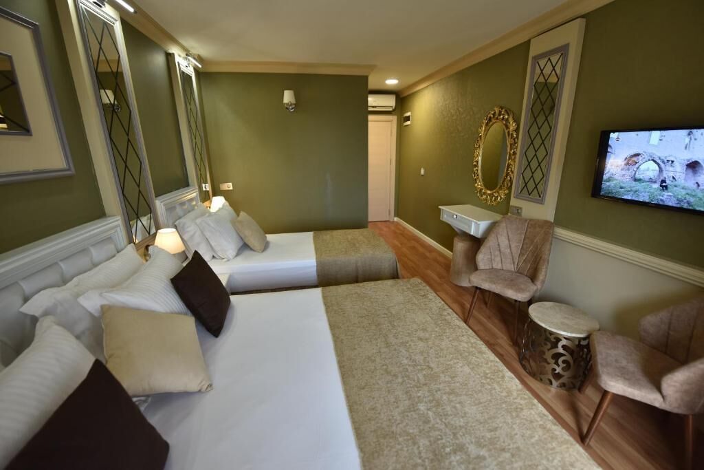 Habitación de hotel con dos camas, un televisor, una silla y una mesita.