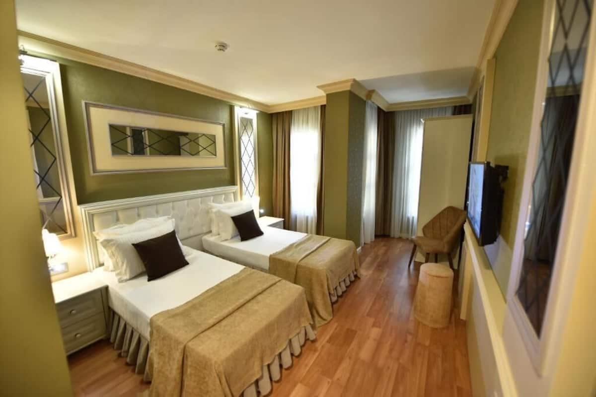 A hotel room with two beds, a television, and a window.