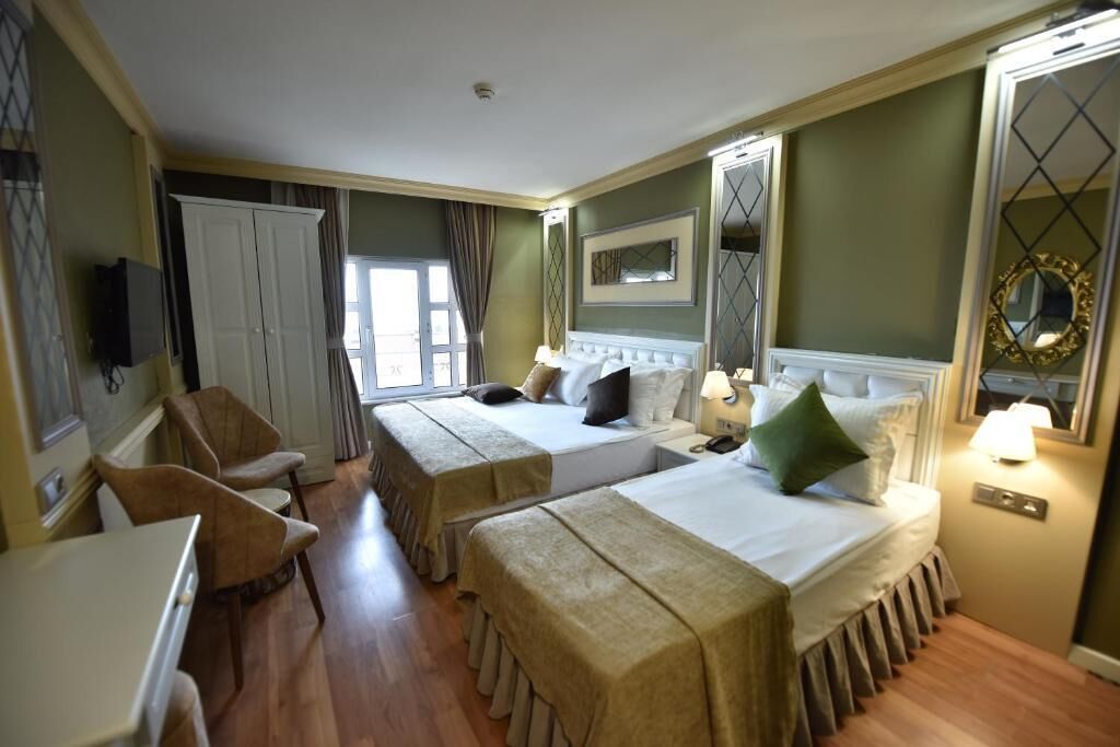 A hotel room with two beds, a desk, a chair, and a television.