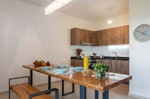 Eine moderne Küche mit Holzschränken, einem Esstisch gedeckt mit Tellern, Gläsern und einer Obstschale.