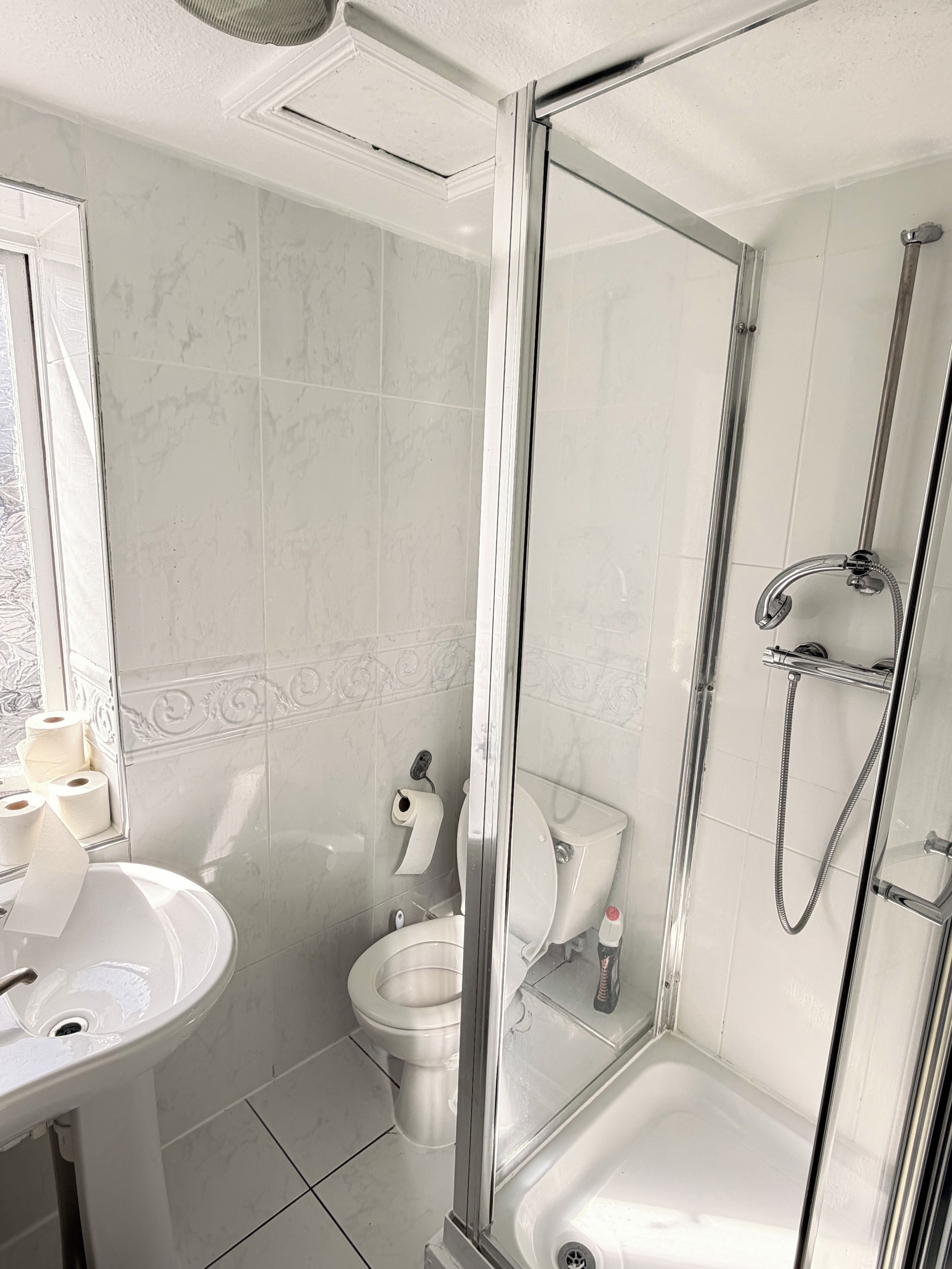 A bathroom with a glass-enclosed shower, a sink, and a toilet.