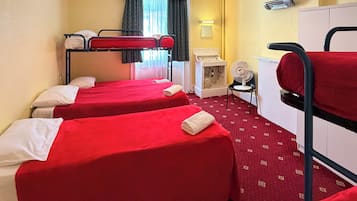 A room with bunk beds, a desk, a chair, a fan, and a heater.