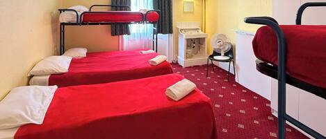 A room with bunk beds, a desk, a chair, a fan, and a heater.