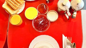 A breakfast table with eggs, bacon, toast, cereal, and various condiments.