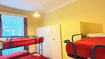 A room with bunk beds, a wardrobe, a door, and a window with curtains.