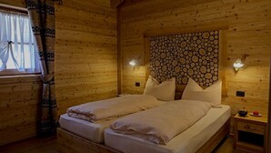 A wooden cabin room with a bed, two bedside tables, and a window with curtains. - Chalet Eco-Lodge Faè - Garden Chalet (Sant'Antonio di Mavignola)