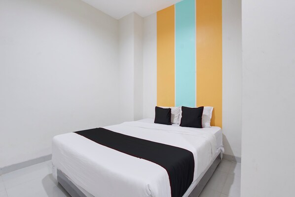 A single-bed room with a white bed, black and white pillows, and a black throw blanket. - Collection O near Stadion Maguwoharjo f (Depok)