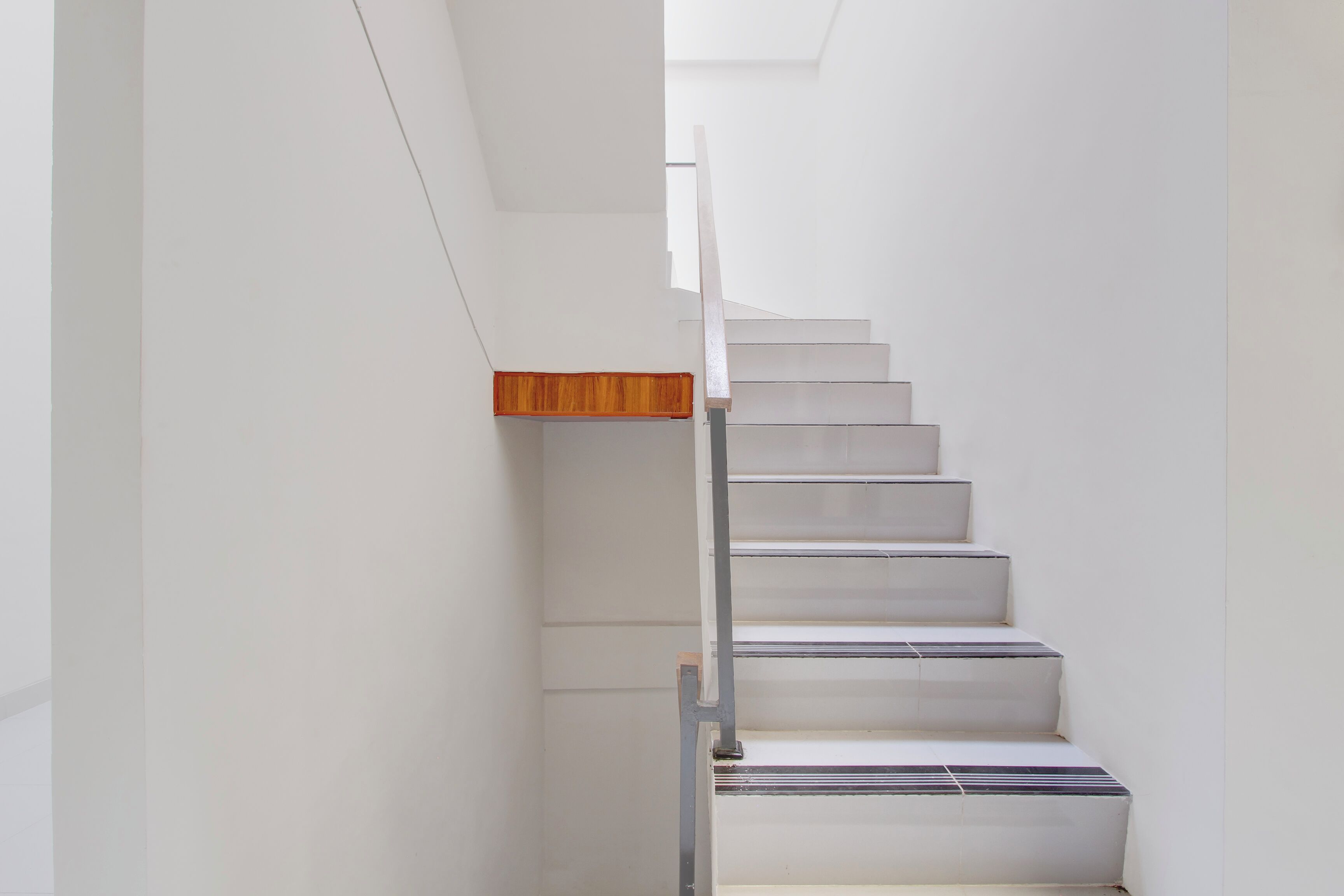 A staircase with a wooden handrail and white walls.