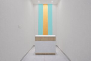 Una recepción en un vestíbulo moderno y minimalista, con una pared lisa y piso de color claro.