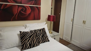 A hotel room with a bed, a zebra-patterned pillow, a red lamp, a large red rose painting, and a wardrobe. - Ground Floor Flat, Free Parking, Near Tube Station (Edgware)