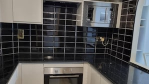 A kitchen with black tiles, stainless steel appliances, and white cabinetry. - Ground Floor Flat, Free Parking, Near Tube Station (Edgware)