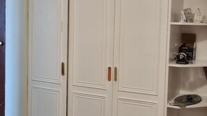 A white wardrobe with two doors, a shelf with decorative items, and a camera on the shelf. - Ground Floor Flat, Free Parking, Near Tube Station (Edgware)