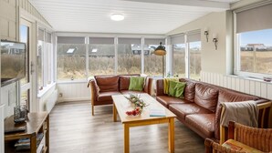 A room with a large window, a sofa, a table, and a wicker chair. - "Myra" - 100m from the sea by Interhome (Løkken)