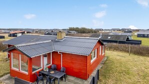 A red mobile home with a patio, a small table, and chairs. - "Myra" - 100m from the sea by Interhome (Løkken)