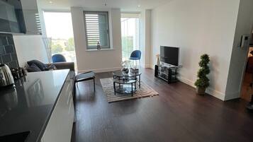 A modern kitchen with a dining area, a TV, and a small potted plant.