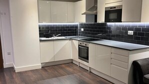 A modern kitchen with white cabinets, a black tiled backsplash, a stainless steel oven, and a black countertop. - Cozy London Apartment With 2 Bedrooms (London)